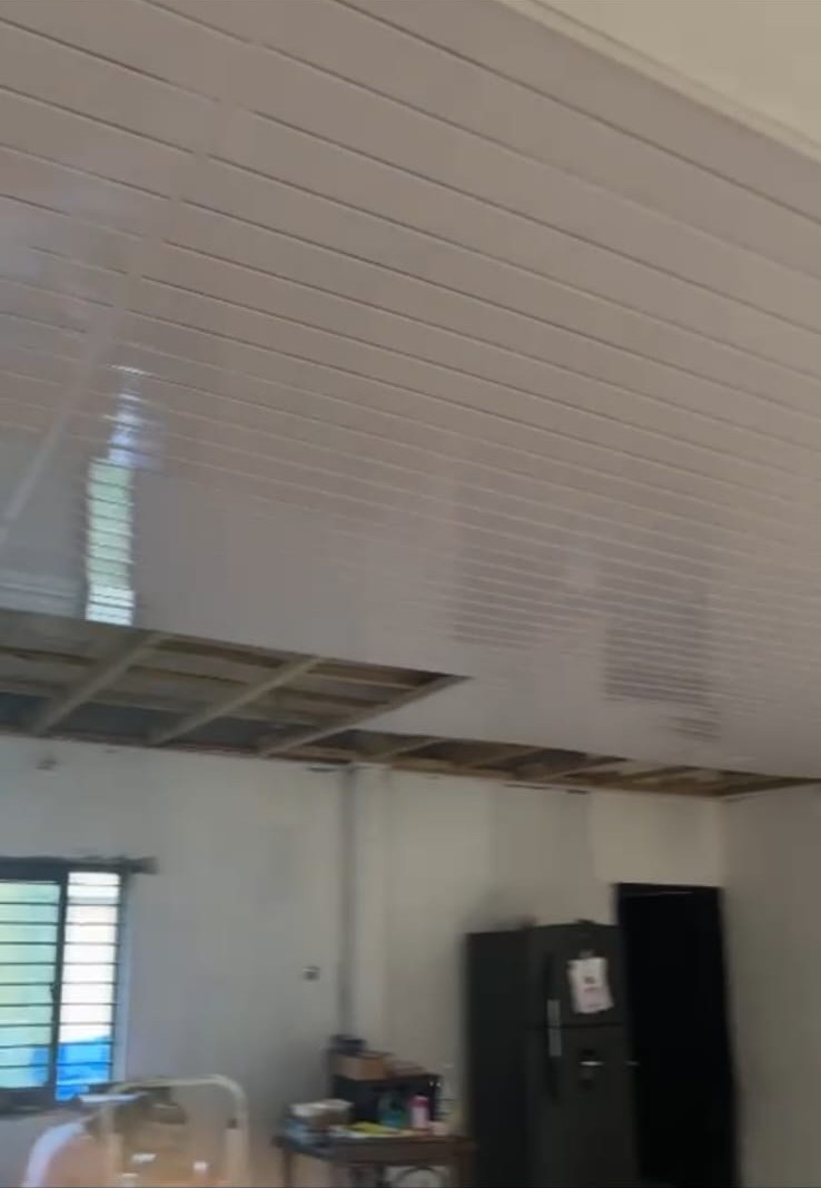 White PVC ceiling panels being installed over timber battens in a residential room